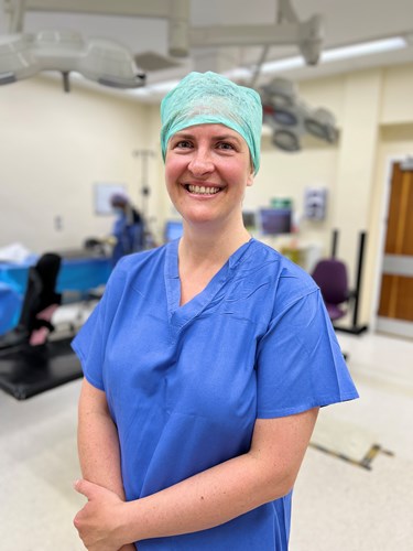 Photo of Sally Pennington, Consultant and Obstetrics and Gynaecology and Clinical Lead for WUTH's Intromed programme, standing in a surgical theatre wearing blue scrubs and theatre cap