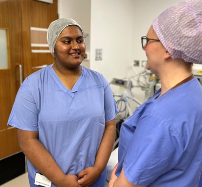 Photo of an Intromed student with a WUTH member of staff wearing blue scrubs and theatre cap standing in an anaesthetic room