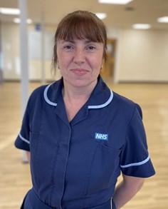 Photo of Anne wearing a navy short sleeved tunic and brown hair tied up